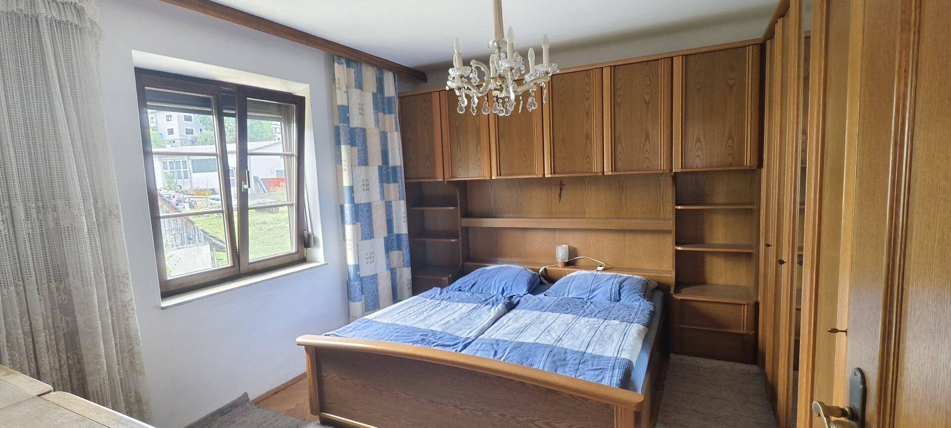 Schlafzimmer mit Doppelbett, Einbauschränken und traditionellem Kronleuchter.