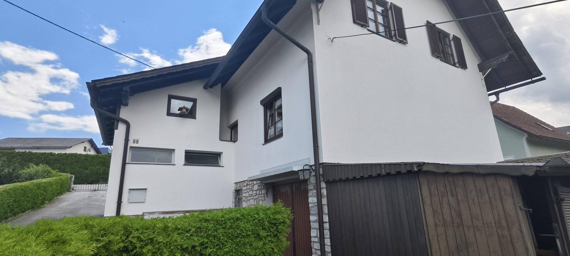 Seitenansicht des Hauses mit Garage, Schuppen und grüner Umgebung.