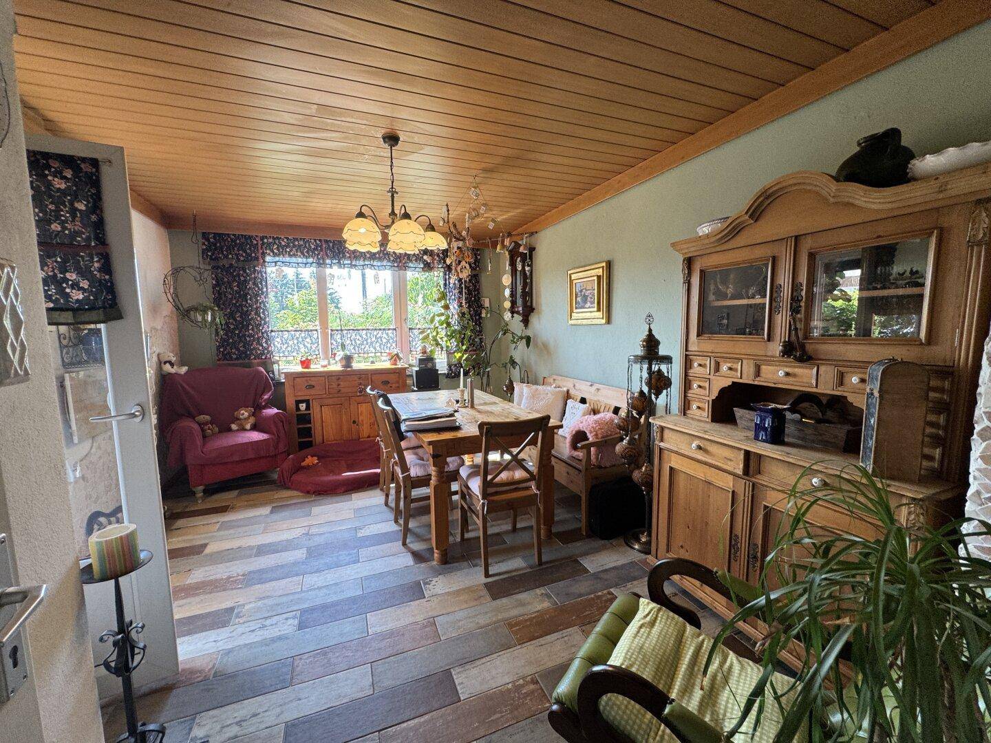 Rustikaler Essbereich mit Holztisch, Stühlen und Schränken unter einer Holzdecke.