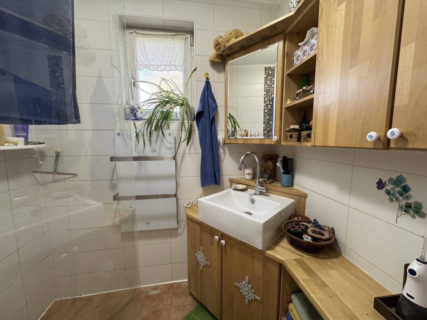 Helles Badezimmer mit Waschbecken, Spiegelschrank und Fliesen an den Wänden.