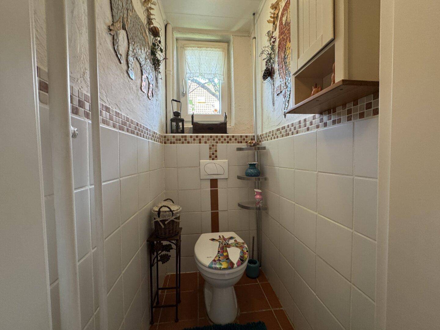 Kleines Gäste-WC mit Wand-WC, Fliesen und einem Fenster für Tageslicht.