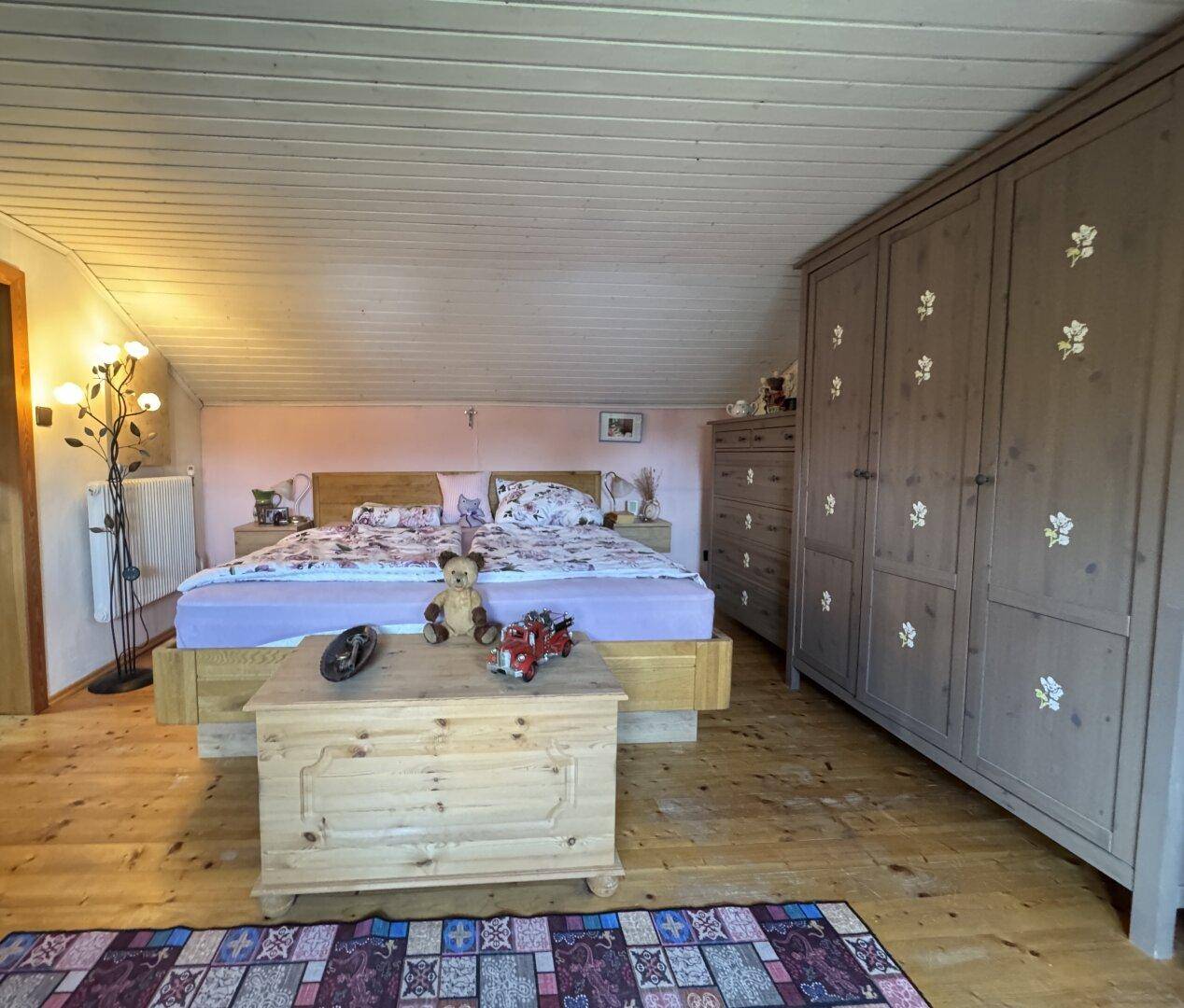 Geräumiges Schlafzimmer im Dachgeschoss mit Doppelbett, Holzschrank und Holzboden.