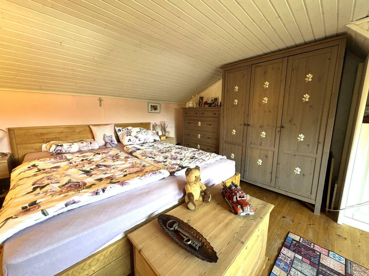 Gemütliches Schlafzimmer im Dachgeschoss mit Doppelbett, Holzschrank und Holzboden.