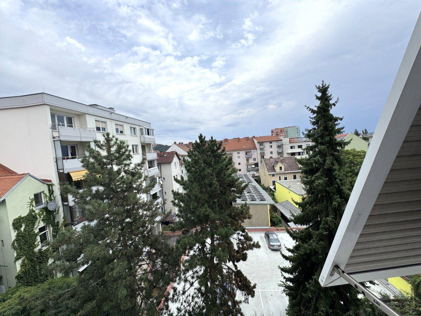 Blick auf die umliegenden Wohngebäude, Bäume und einen Parkplatz von oben.