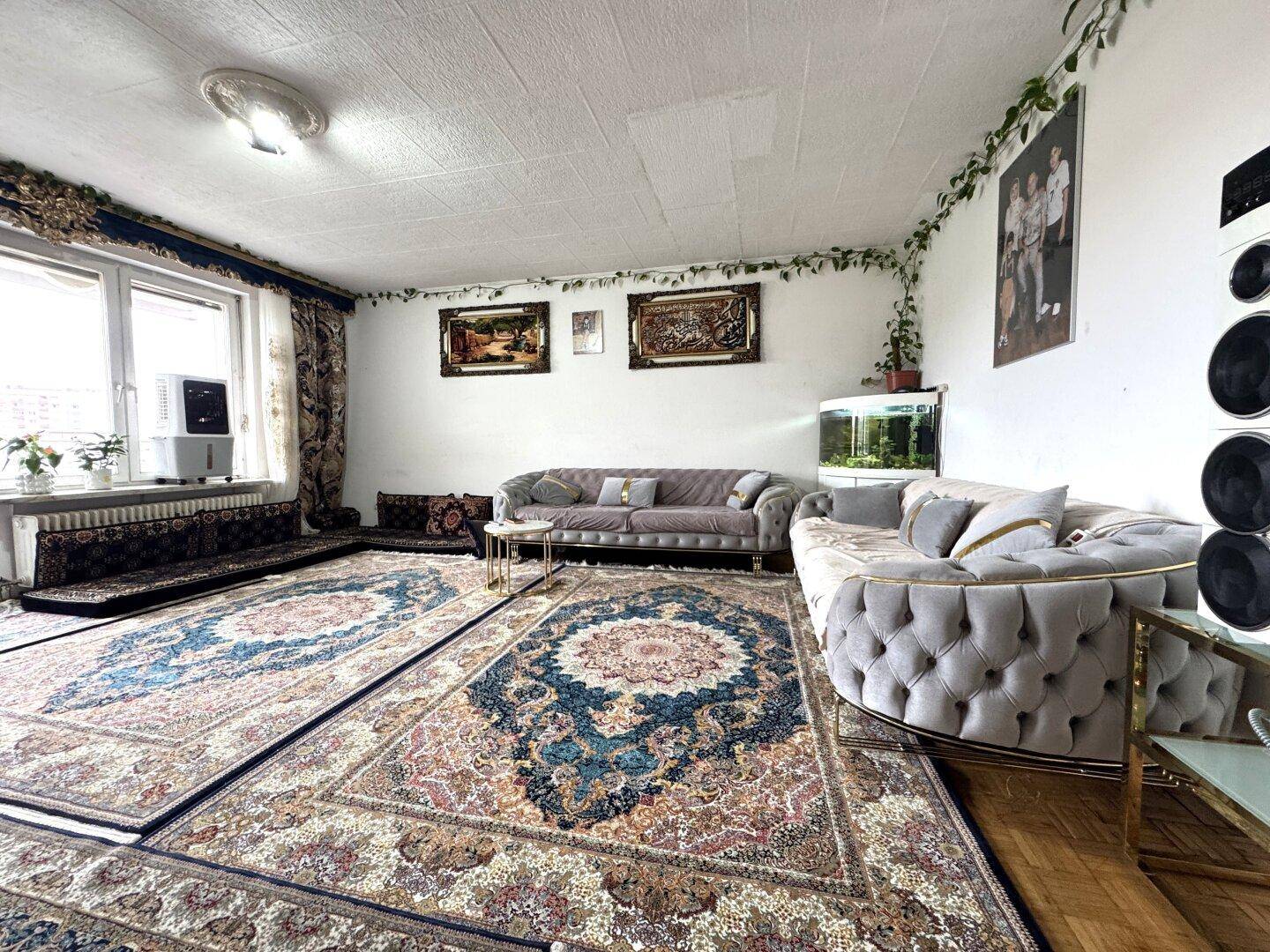 Geräumiges Wohnzimmer mit mehreren Sofas, orientalischen Teppichen und einem Aquarium.