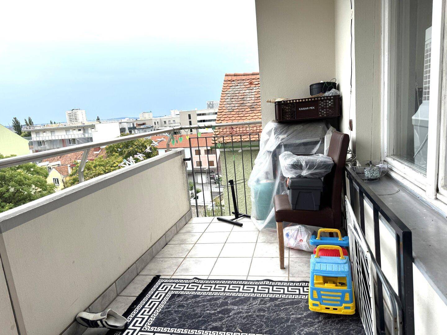 Balkon mit Blick auf die Stadt, derzeit als Abstellfläche genutzt, mit Kinderspielzeug.