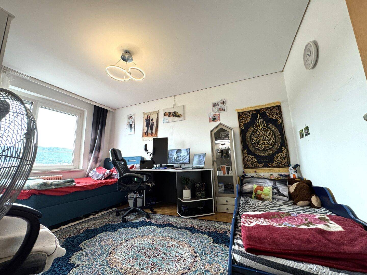 Kinder- oder Gästezimmer mit zwei Betten, einem Schreibtisch und einem Fenster.