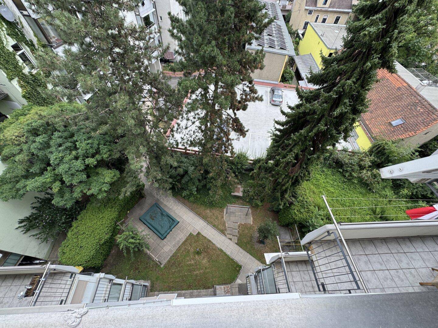 Blick von oben auf einen begrünten Innenhof mit Wegen und Bäumen.