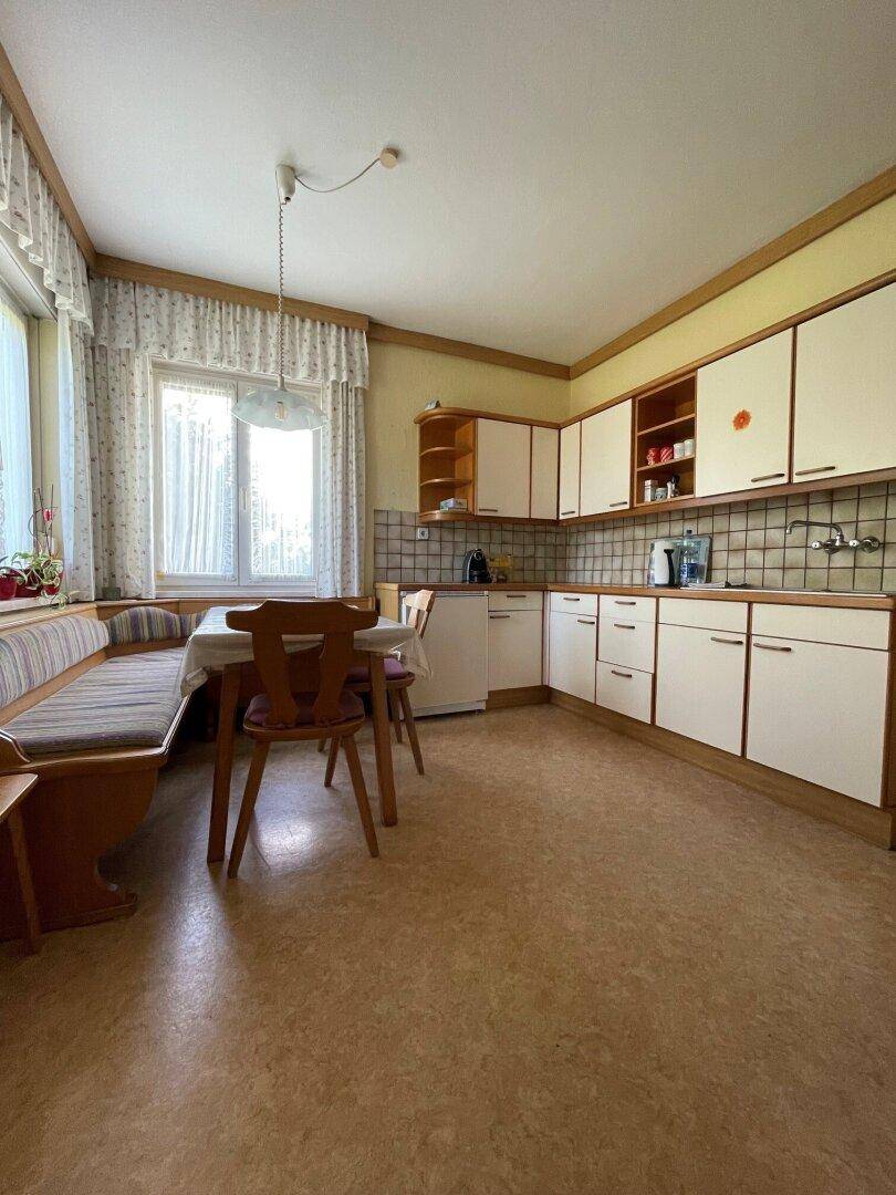 Geräumige Wohnküche mit traditionellen Einbauschränken und einem gemütlichen Essbereich am Fenster.