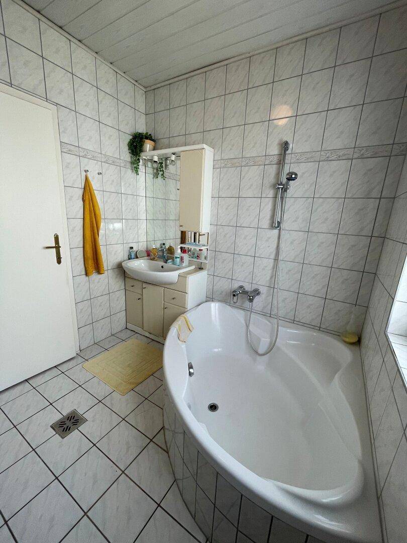 Helles Badezimmer mit runder Badewanne, Waschbecken und Spiegelschrank.