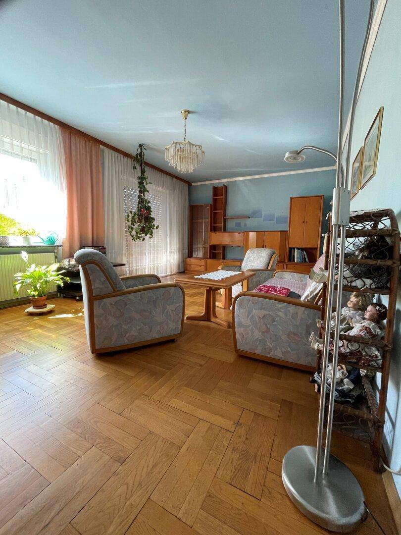 Gemütliches Wohnzimmer mit Fischgrätparkett, blauen Wänden und traditionellen Möbeln.