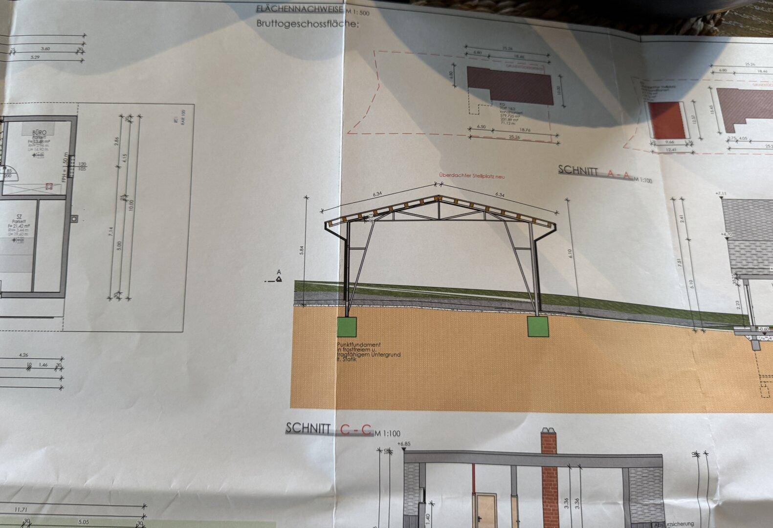 Detailansicht eines Schnitts mit Carport-Struktur und weiteren Gebäudeteilen auf einem Hanggrundstück.