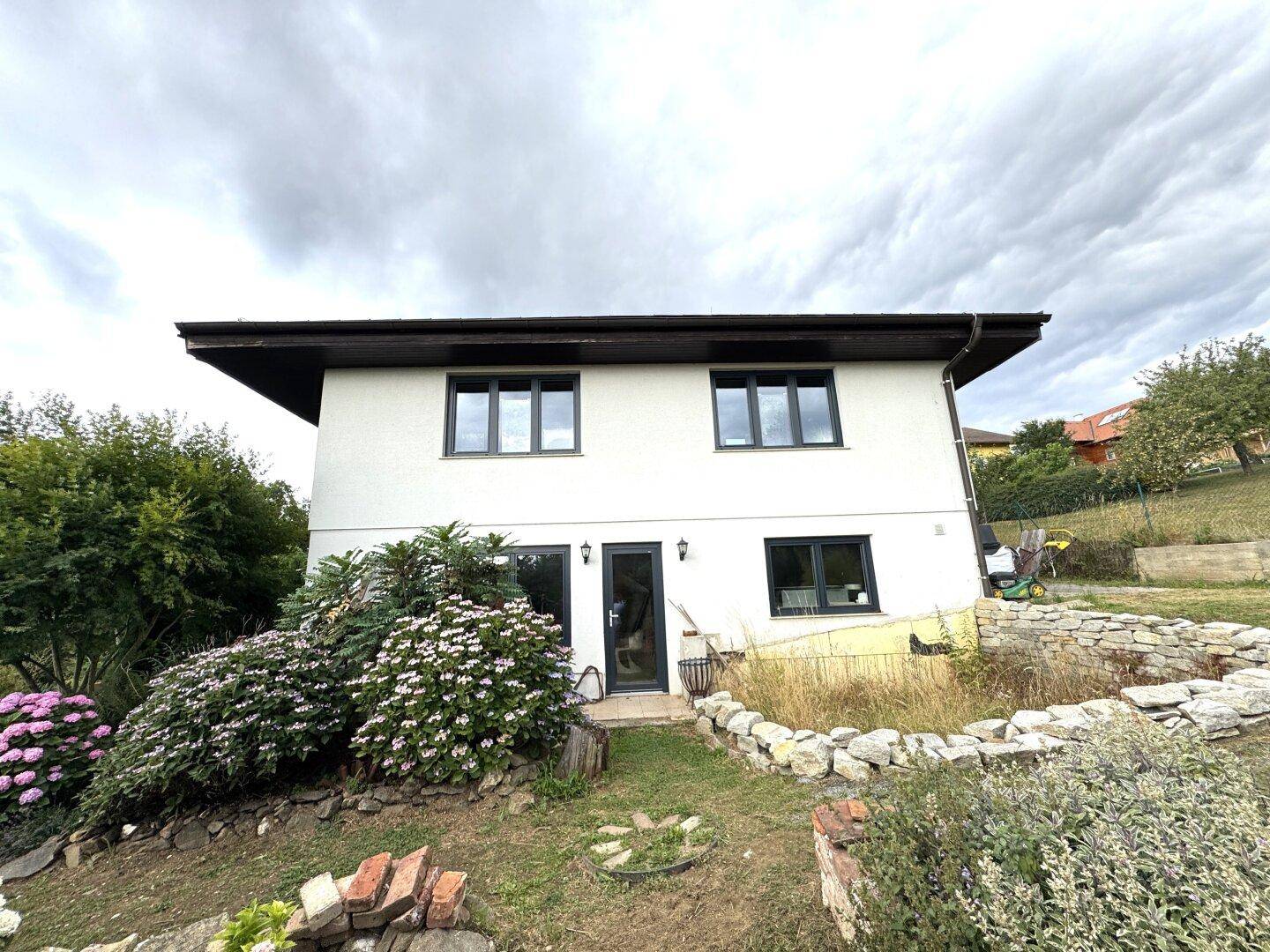 Rückseite des Hauses mit Zugang zum Gartenbereich und Fenstern im Erdgeschoss.