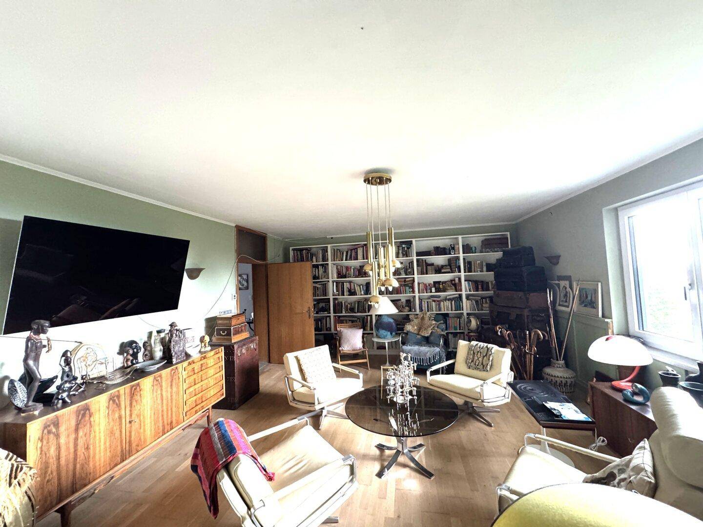 Helles Wohnzimmer mit großem Fernseher, Mid-Century-Möbeln und einer Bücherwand.