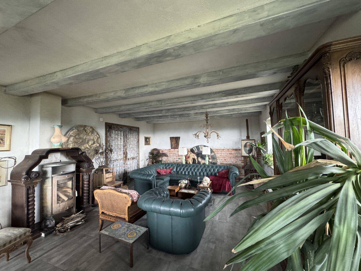 Gemütliches Wohnzimmer mit sichtbaren Deckenbalken, traditionellen Möbeln und einem Holzofen.