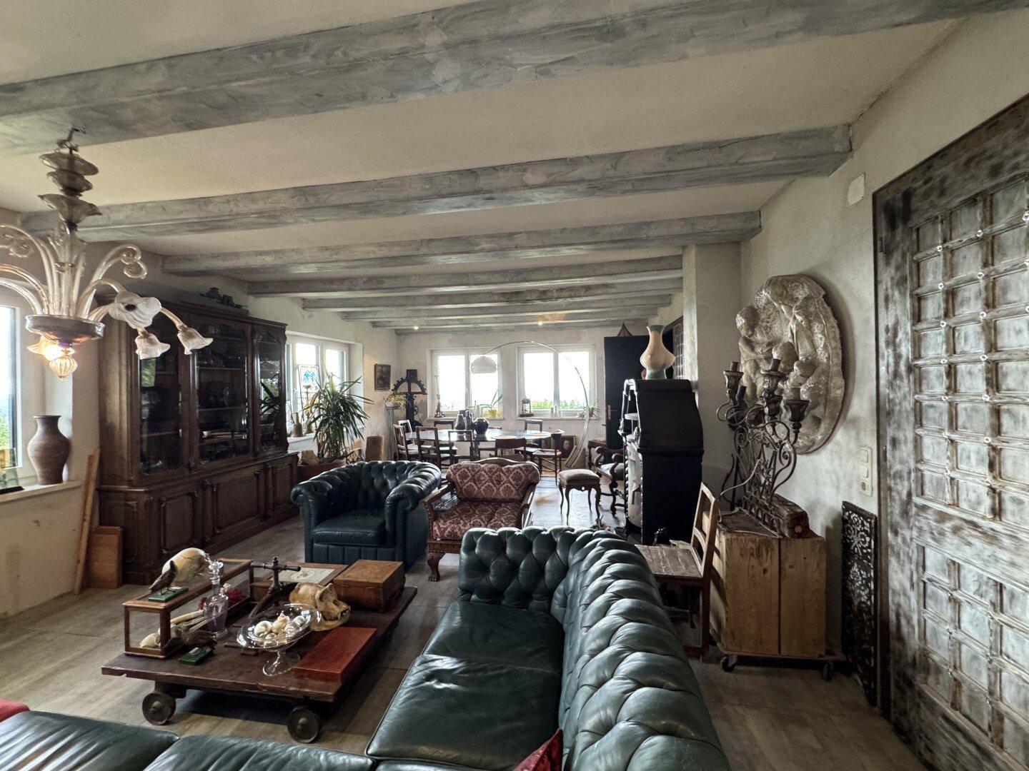 Geräumiger Wohn-Essbereich mit traditionellen Möbeln, Holzbalken und einem großen Holzschrank.