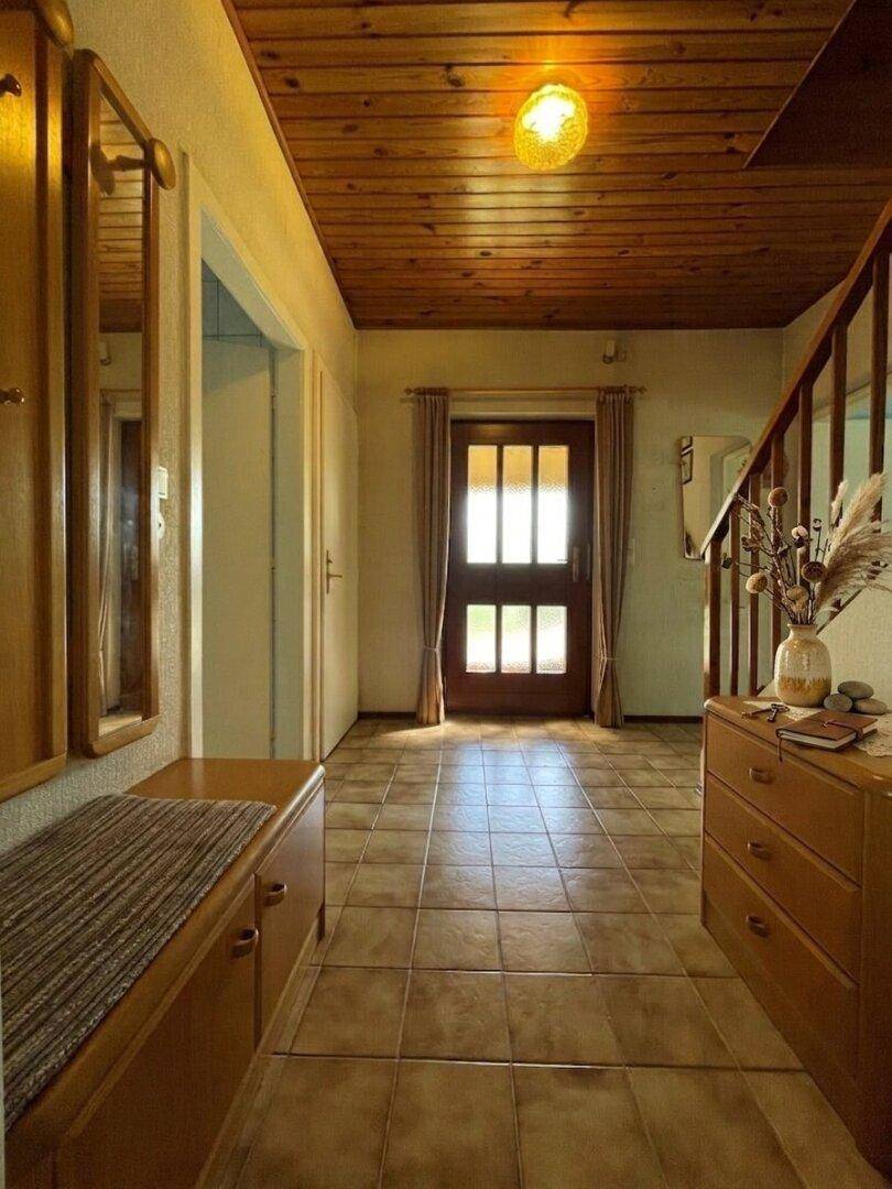 Heller Flur mit Fliesenboden, Holzdecke und Garderobenmöbeln im Landhausstil.