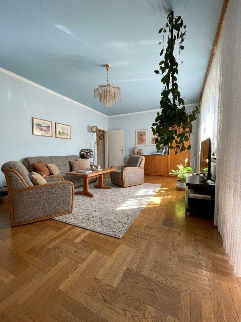 Helles Wohnzimmer mit Holzboden, bequemer Couch und dekorativen Pflanzen.