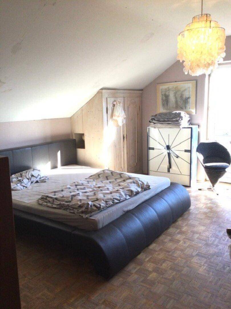 Schlafzimmer im Dachgeschoss mit schrägen Wänden, Doppelbett und Holzboden.