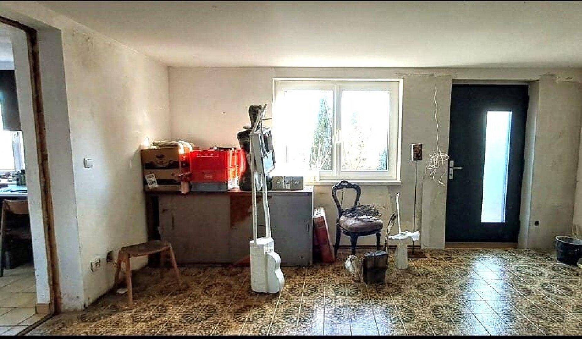 Raum in Renovierung mit gemustertem Fliesenboden und einem Fenster zur Außenseite.