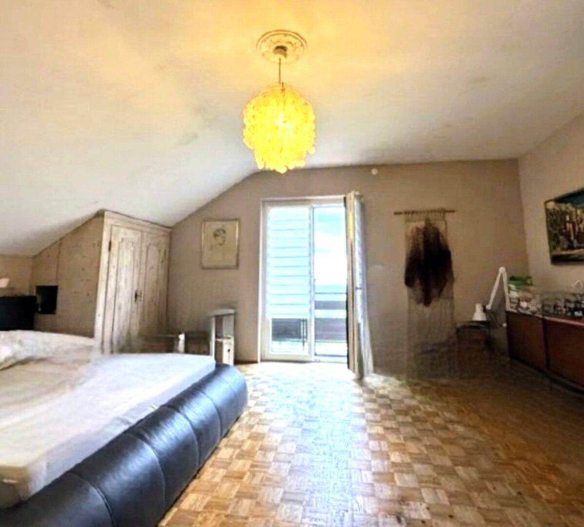 Schlafzimmer im Dachgeschoss mit Zugang zu einem Balkon und Holzboden.