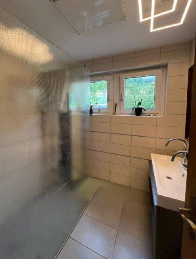 Modernes Badezimmer mit Dusche, Doppelwaschbecken und Fenster.