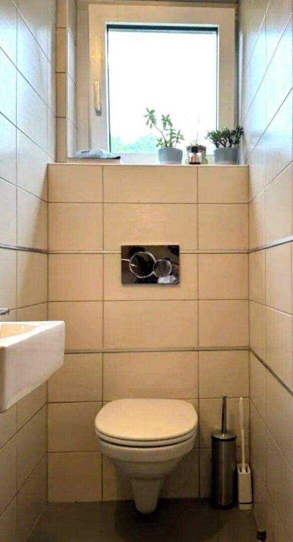 Kleines Gäste-WC mit Wand-WC, Waschbecken und Fenster.