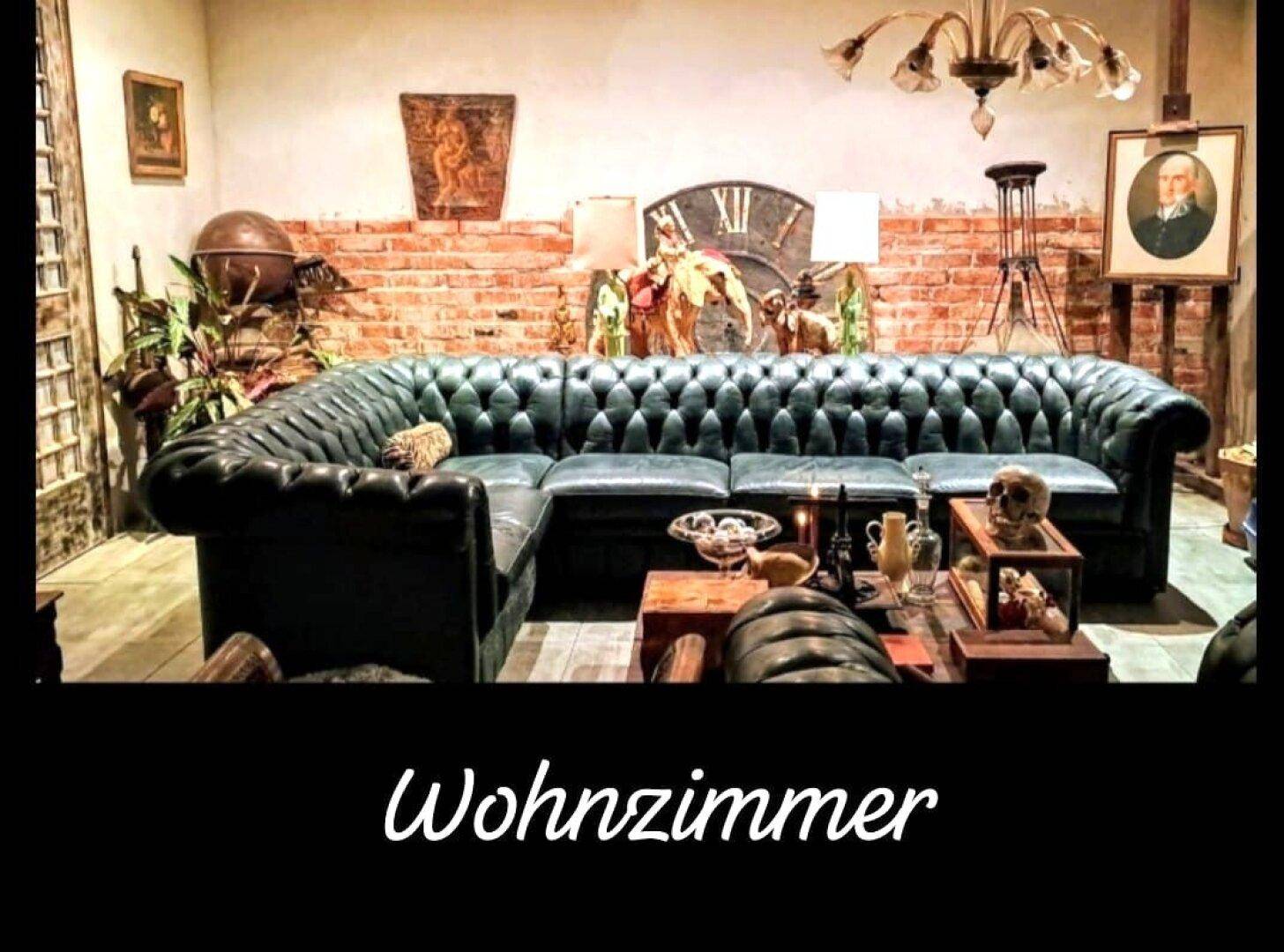 Klassisches Wohnzimmer mit Chesterfield-Sofa, Ziegelwand und antiken Dekorationen.
