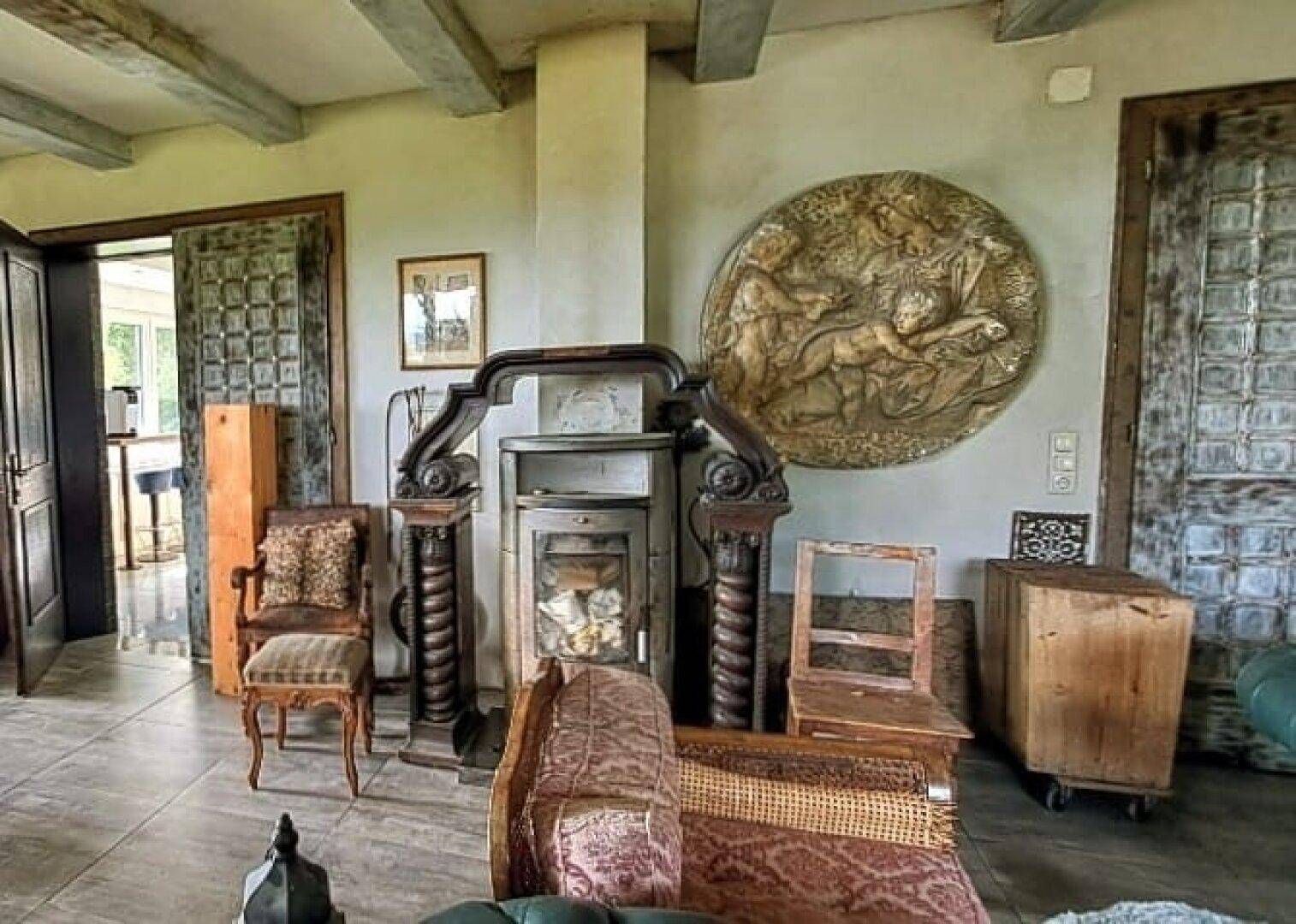 Geräumiges Wohnzimmer mit Kaminofen, Kunstwerk und Zugang zu weiteren Räumen.