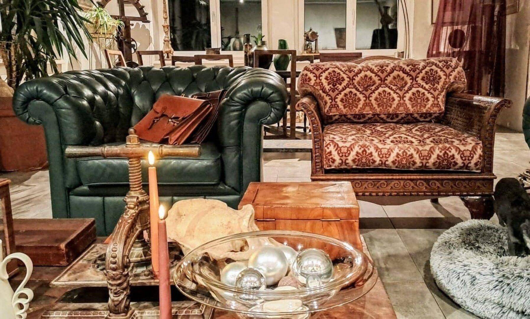 Gemütliches Wohnzimmer mit Chesterfield-Sofa, gemustertem Sessel und stimmungsvoller Dekoration.