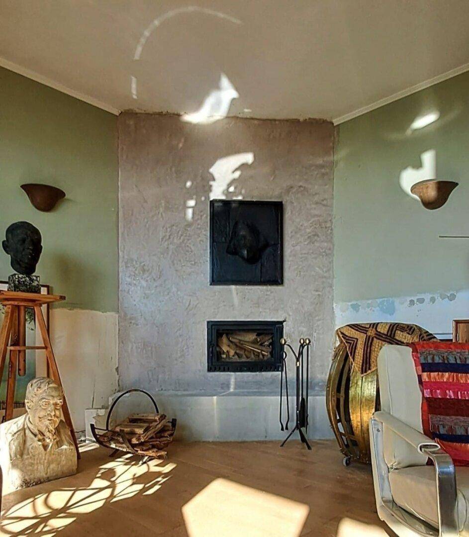 Helles Wohnzimmer mit modernem Kamin, hellgrünen Wänden und Holzboden.