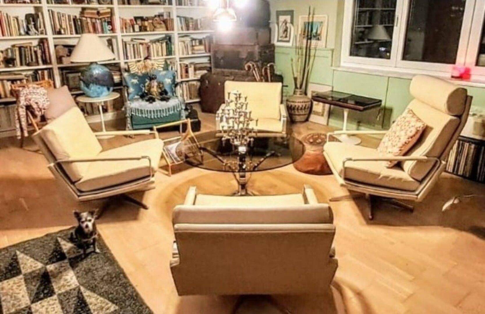 Wohnzimmer mit umfangreicher Bücherwand, mehreren Sesseln und gemütlicher Atmosphäre.