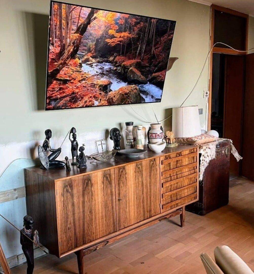 Bereich mit elegantem Holz-Sideboard, großem Fernseher und dekorativen Elementen.