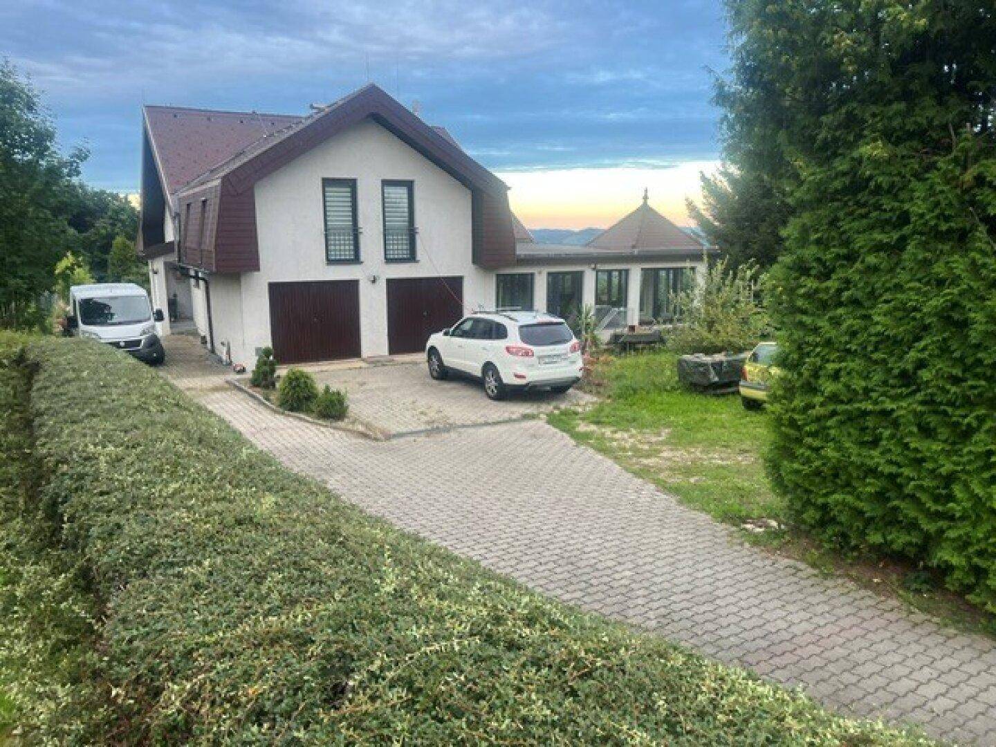 Wohnhaus mit Doppelgarage, gepflasterter Auffahrt und großem Gartenbereich.