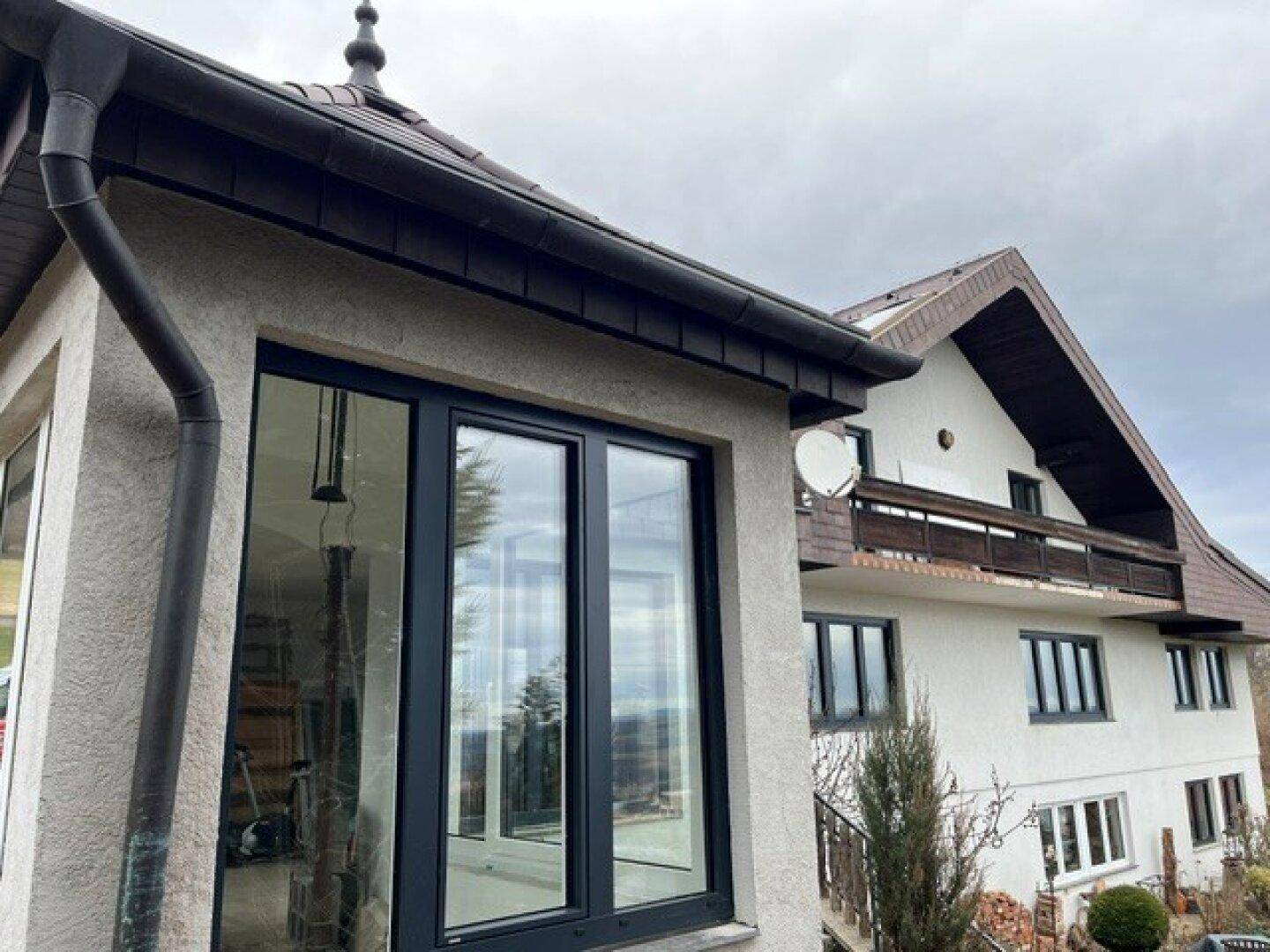 Moderner Anbau mit großen Fenstern und Blick auf das Haupthaus mit Balkon.