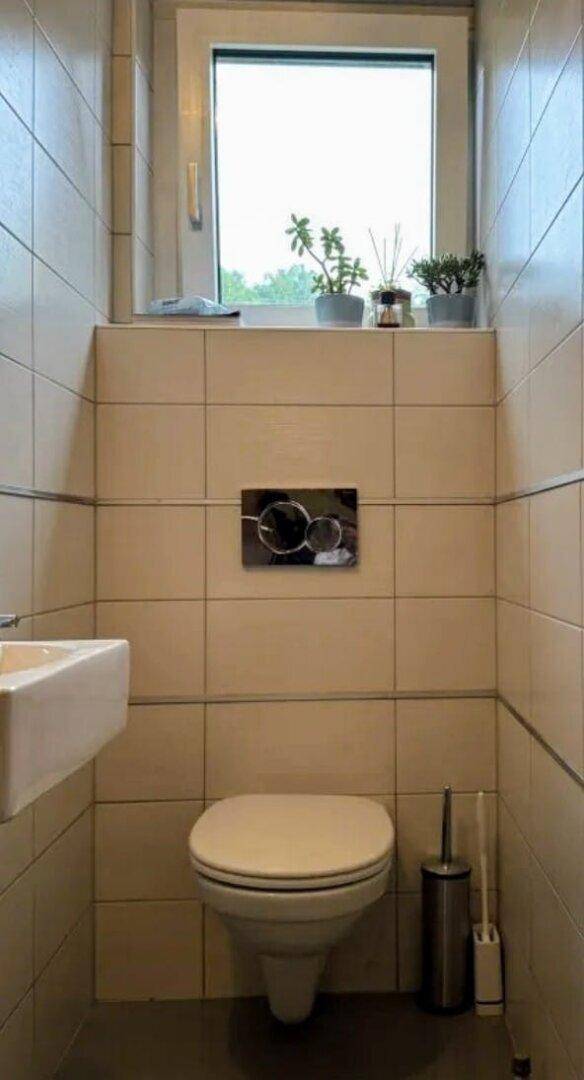 Kleines Gäste-WC mit wandhängender Toilette, Waschbecken und Fenster.
