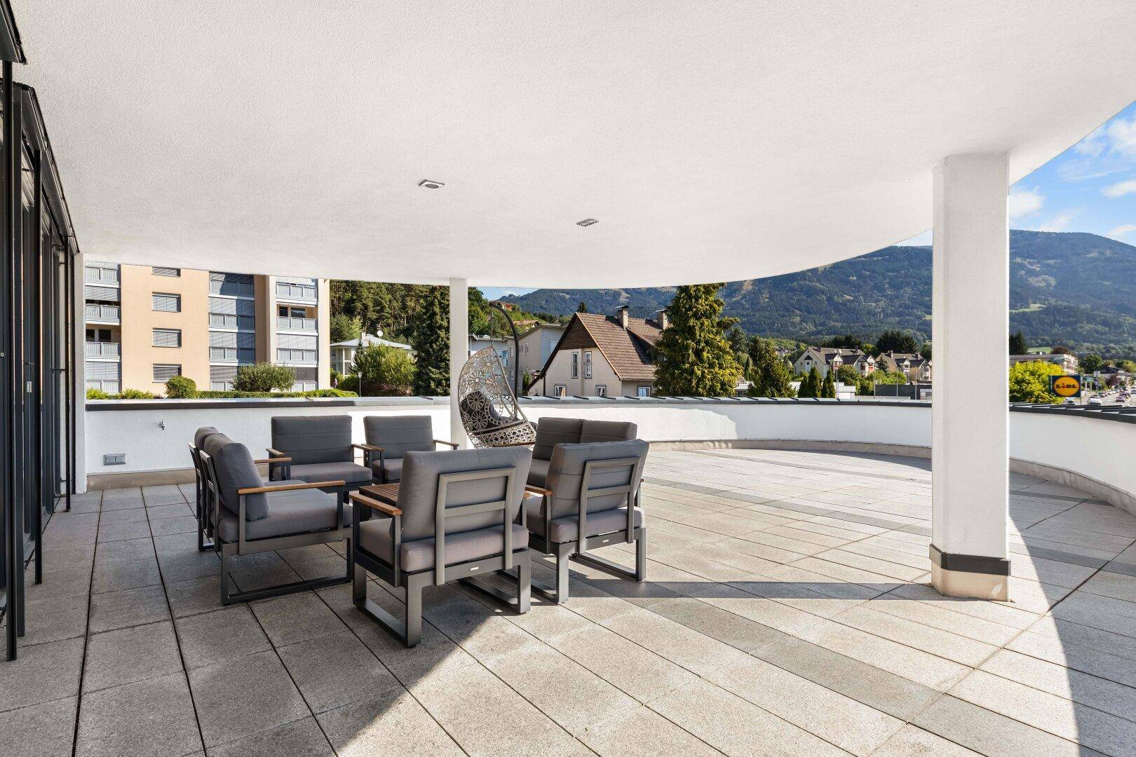 Großzügige Terrasse mit modernen Sitzgelegenheiten und weitem Blick auf die Berge und Umgebung.