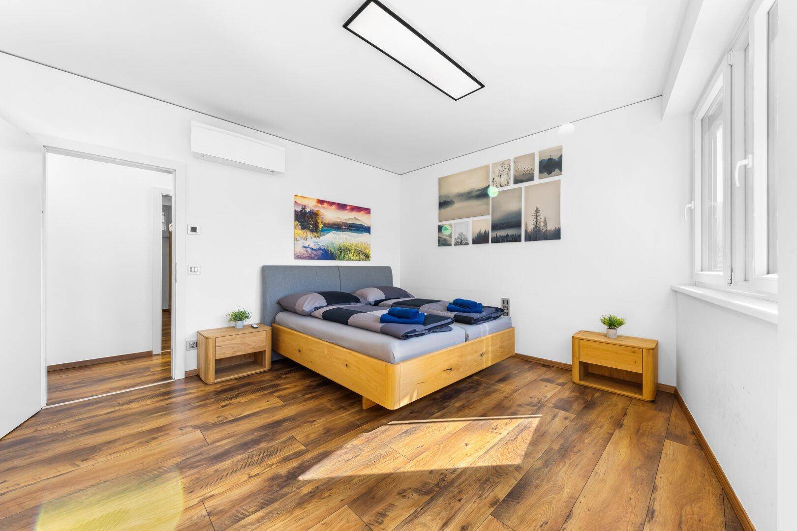 Gemütliches Schlafzimmer mit Holzbett, Nachttischen und Klimaanlage.