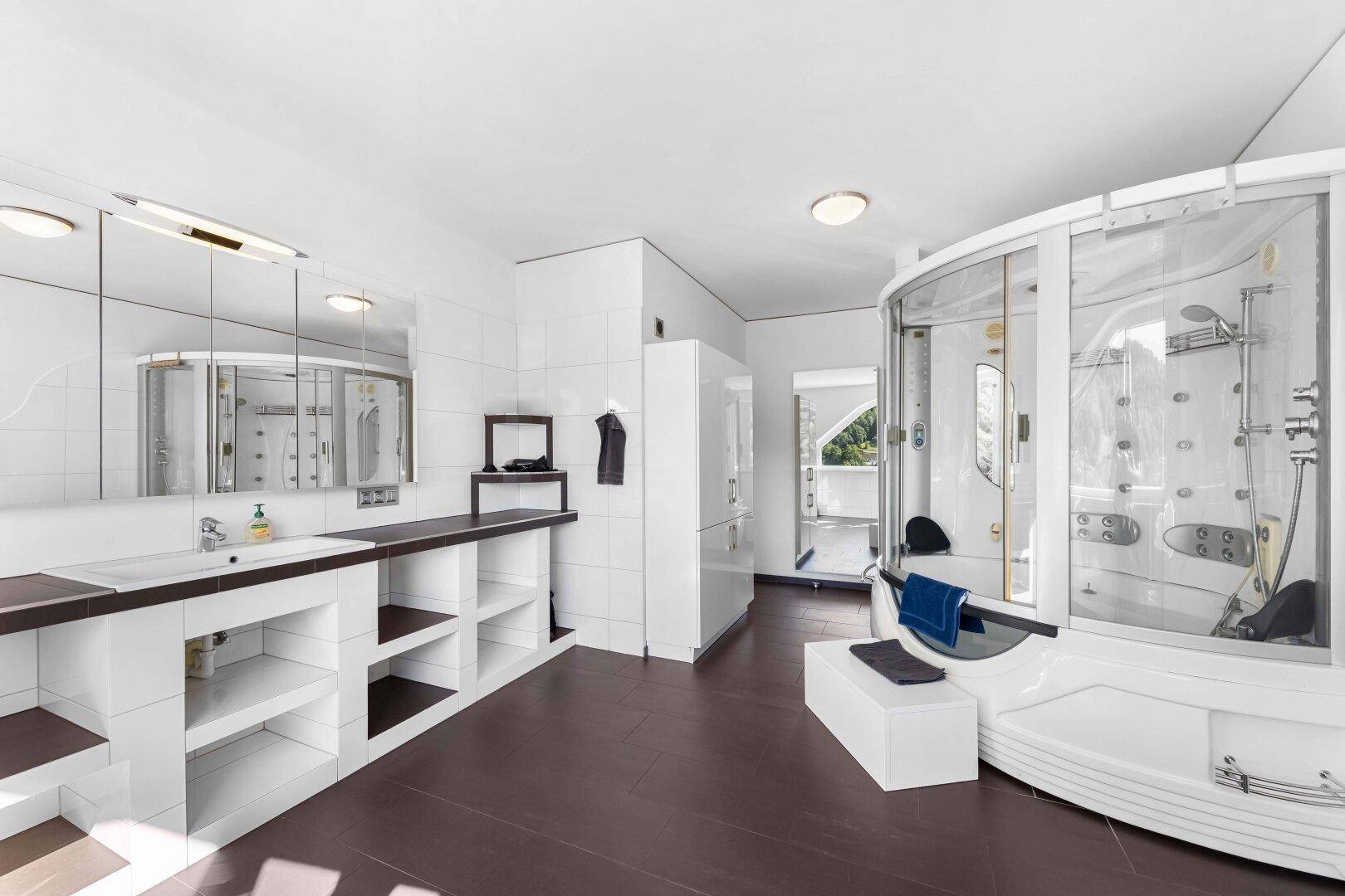 Geräumiges Badezimmer mit Doppelwaschbecken, großer Duschkabine und dunklem Fliesenboden.