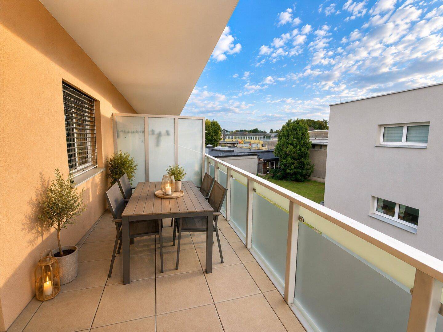 Möblierter Balkon mit Fliesenboden und Blick auf die Umgebung.