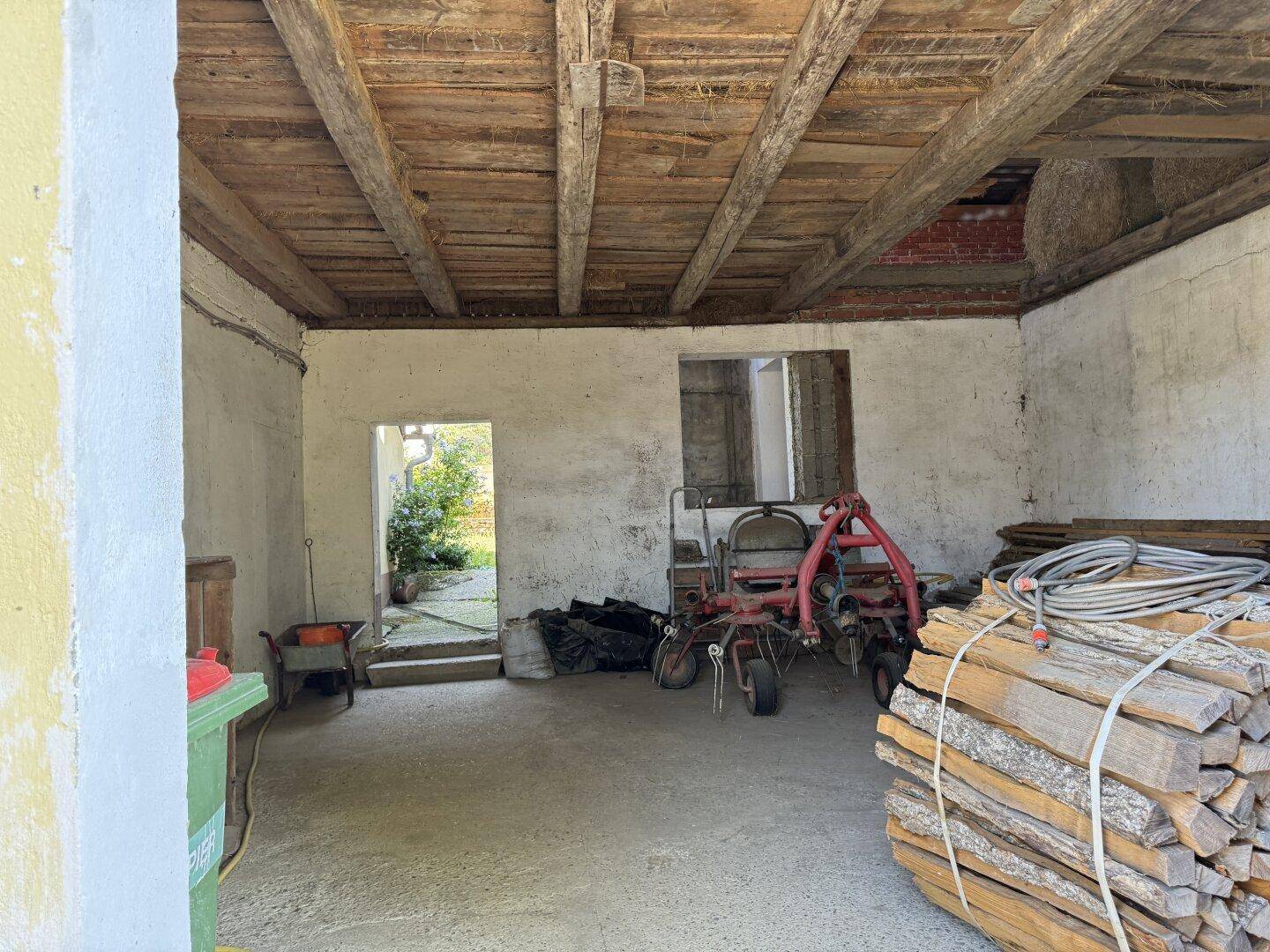 Werkstattraum mit Holzbalkendecke, Betonboden und Zugang zum Gartenbereich.