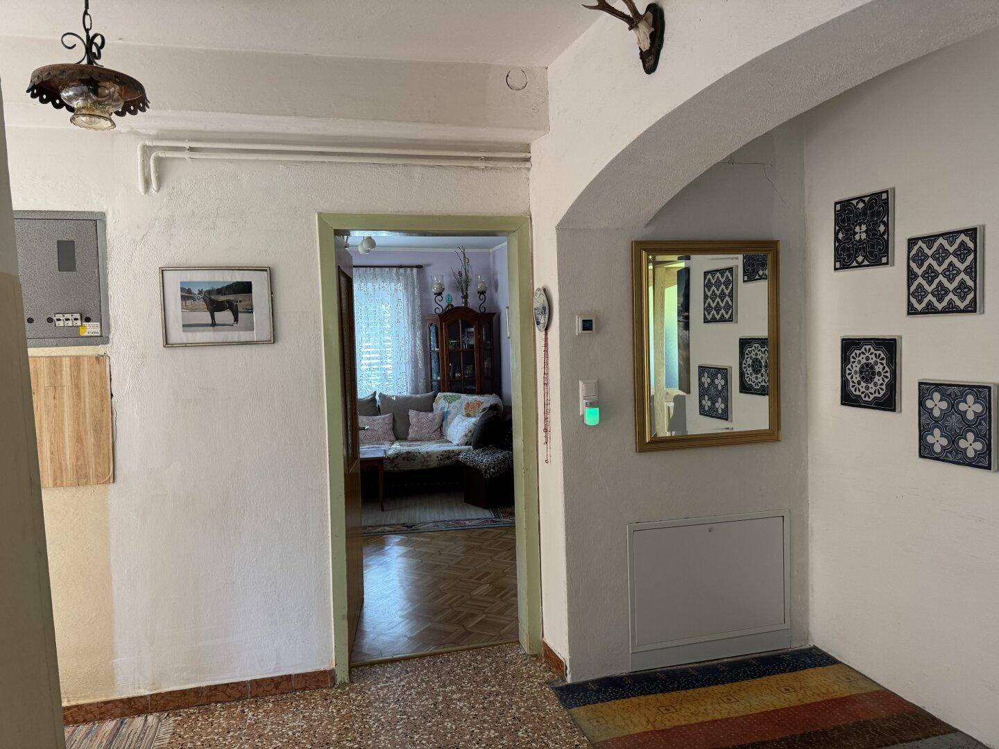 Flur mit Terrazzoboden, weiß gestrichenen Wänden und Durchgang zu weiteren Räumen.