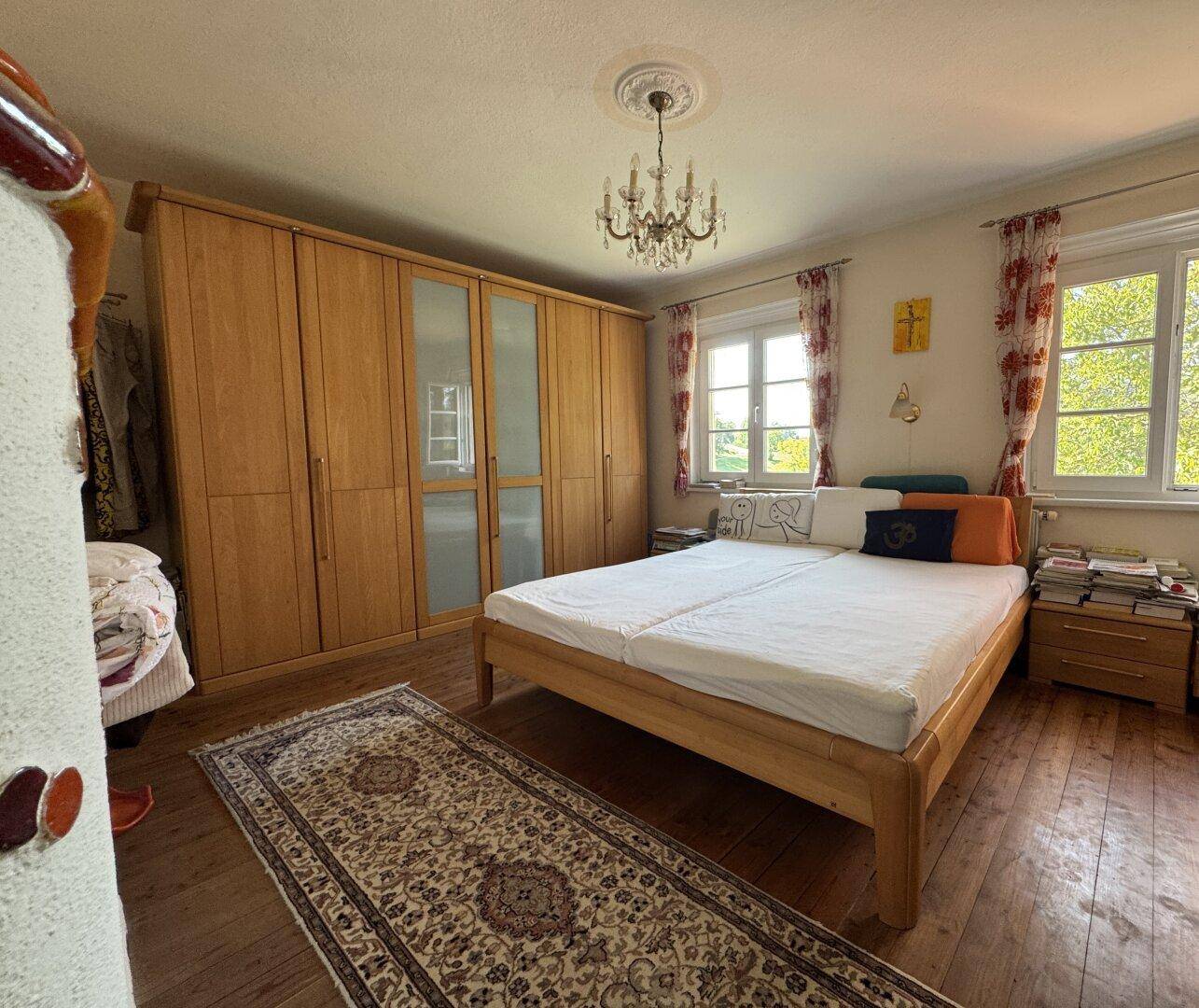 Schlafzimmer mit Holzboden, großem Kleiderschrank und Kronleuchter an der Decke.