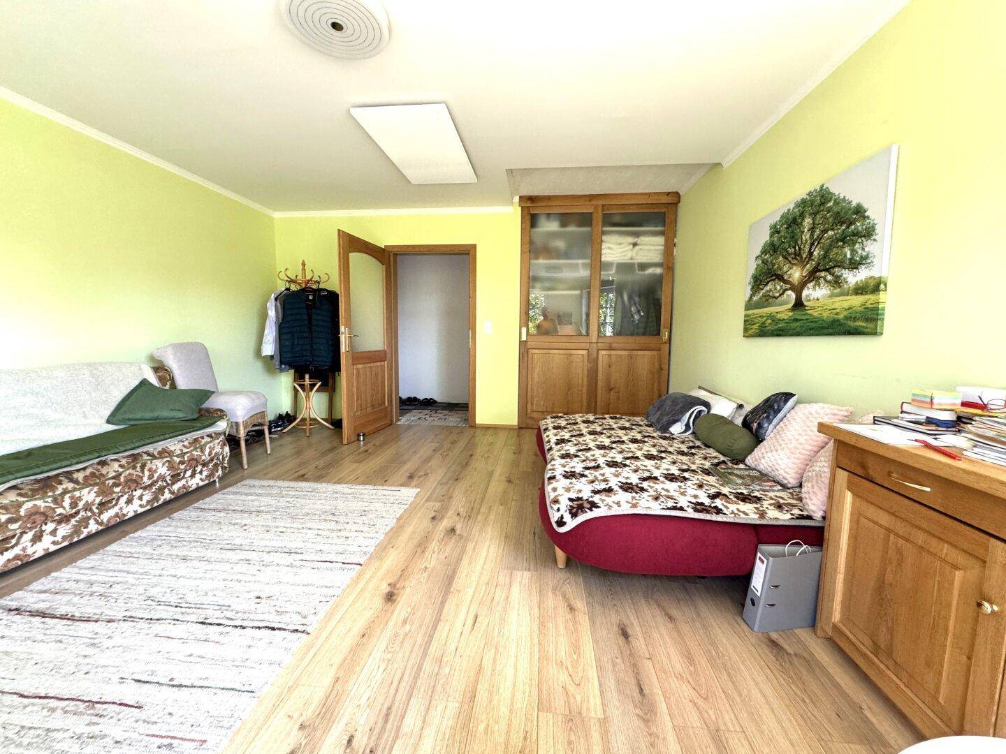 Heller Raum mit Holzboden, grünen Wänden und vielseitiger Nutzung als Wohn- oder Arbeitsbereich.