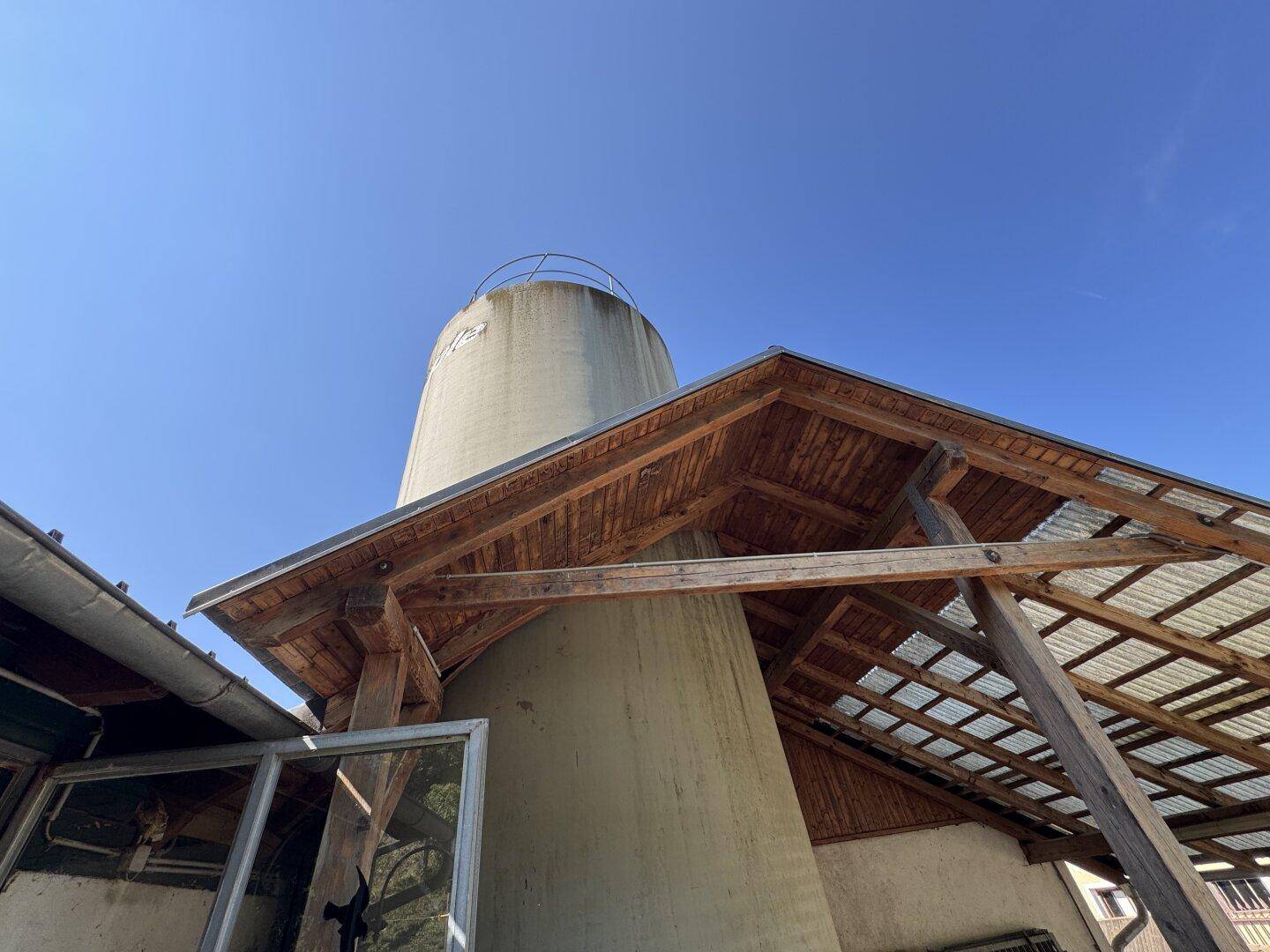Nahaufnahme eines Silos mit einer hölzernen Dachkonstruktion unter strahlend blauem Himmel.