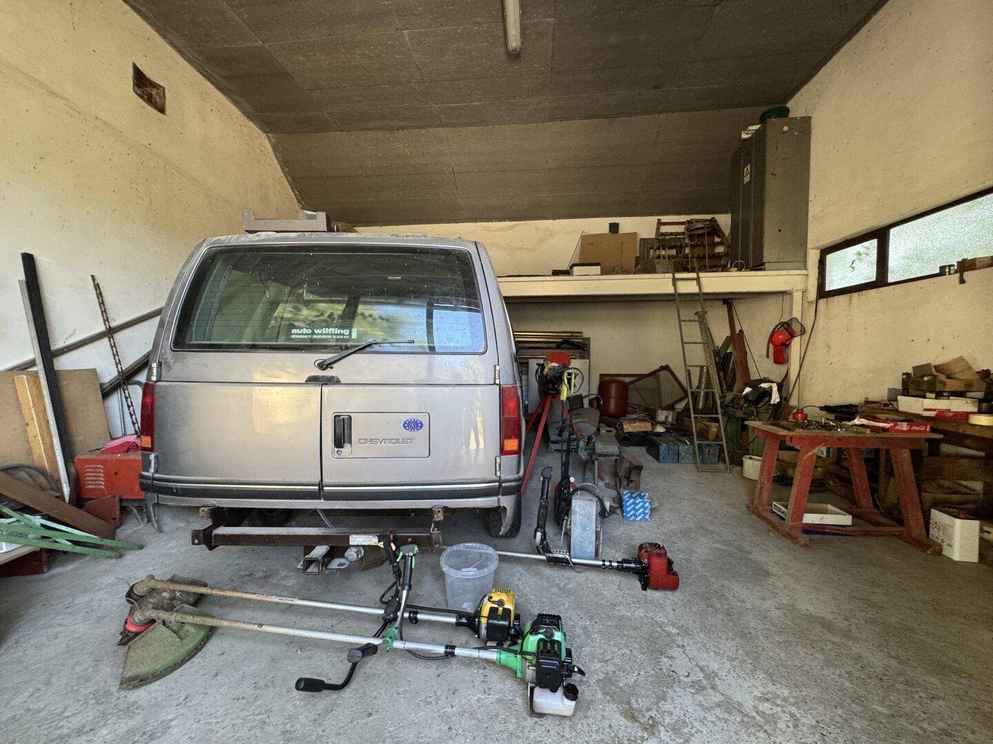 Geräumige Garage mit einem Van und verschiedenen Werkzeugen, ideal als Werkstatt oder Lager.