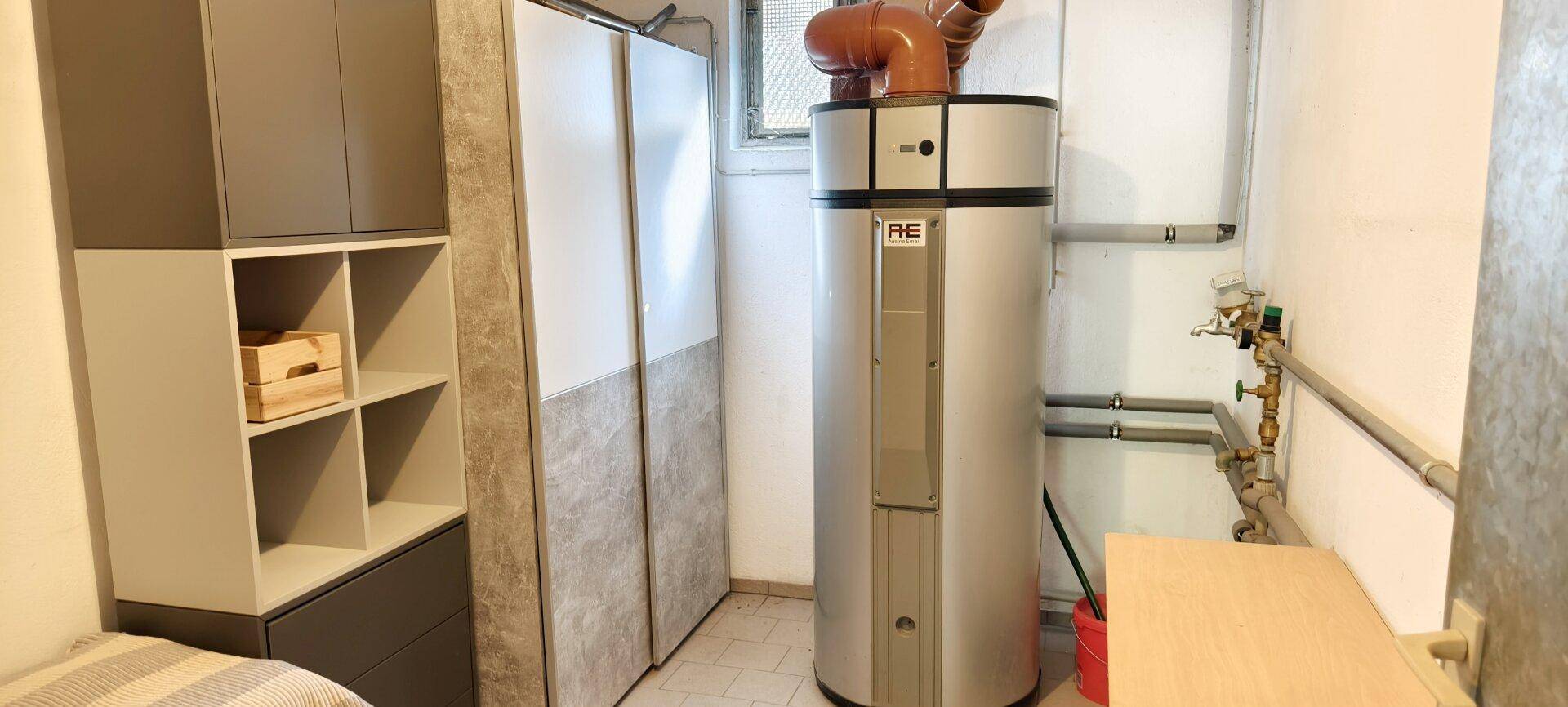 Praktischer Hauswirtschaftsraum mit Warmwasserboiler und zusätzlichen Ablagemöglichkeiten.