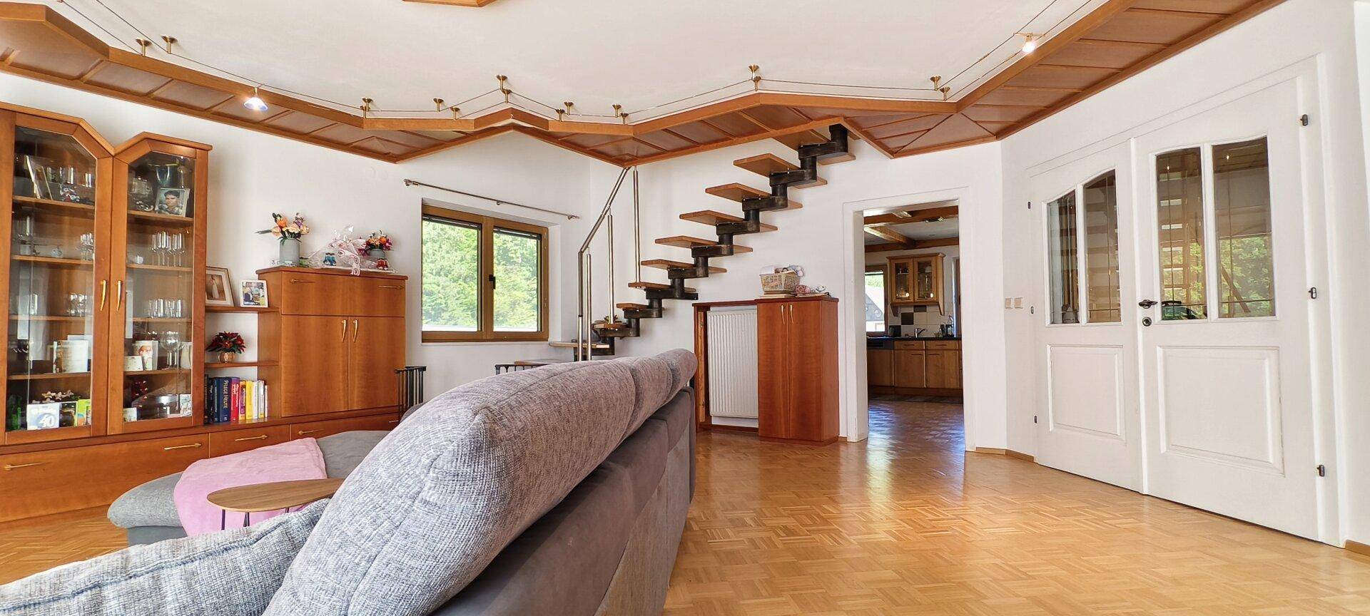 Offener Wohnbereich mit Holztreppe, Parkettboden und Blick in die Küche.
