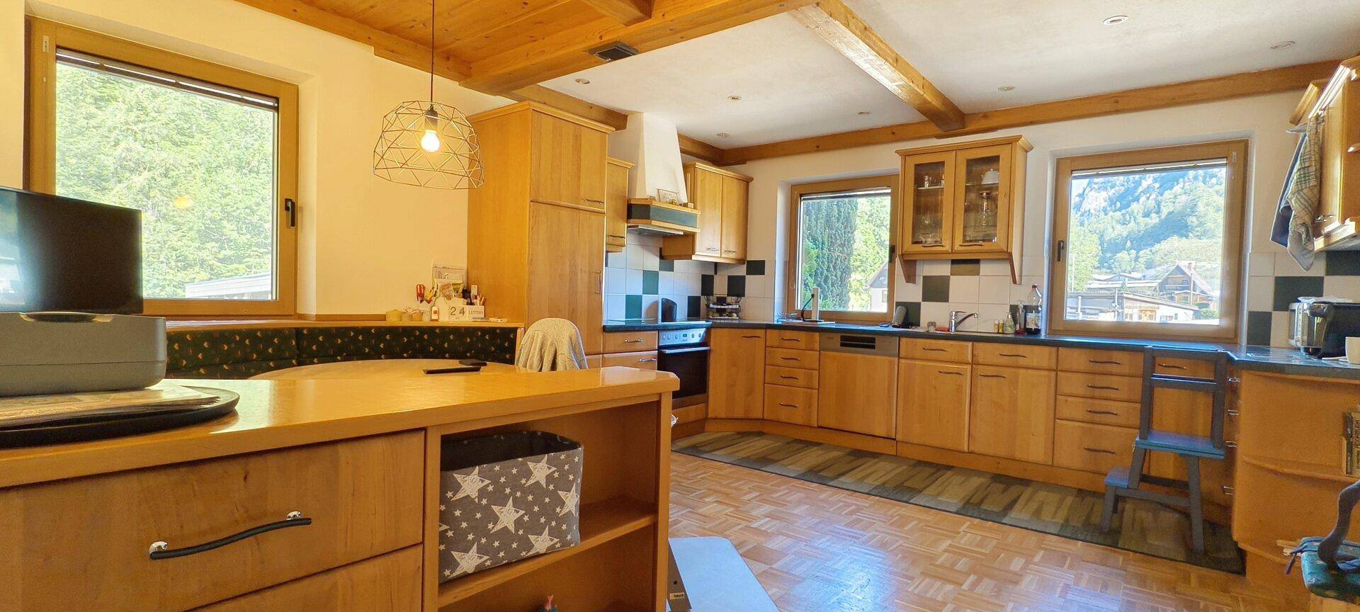 Helle Holzküche mit modernen Geräten, viel Arbeitsfläche und malerischem Bergblick aus den Fenstern.