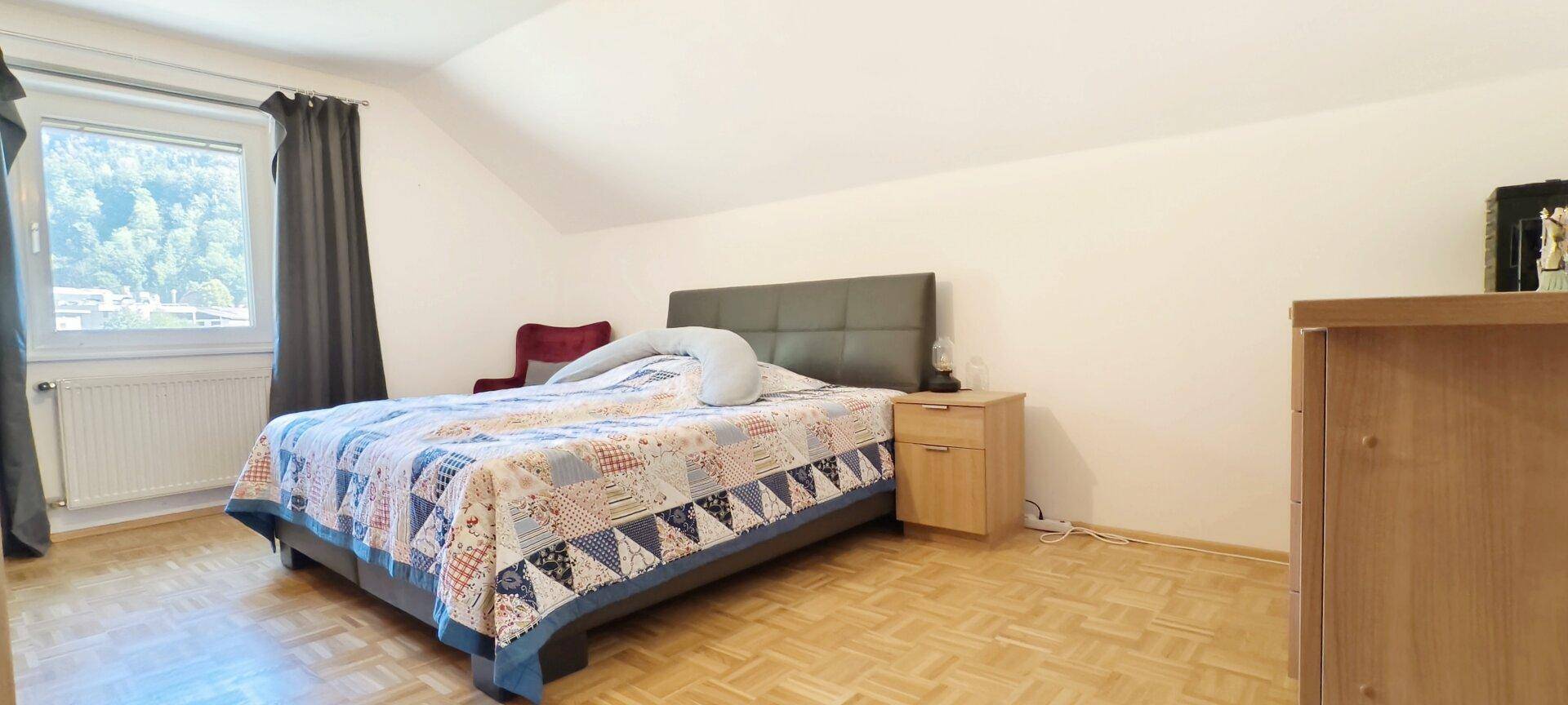 Gemütliches Schlafzimmer mit Doppelbett, Holzboden und Dachschräge, bietet einen ruhigen Rückzugsort.